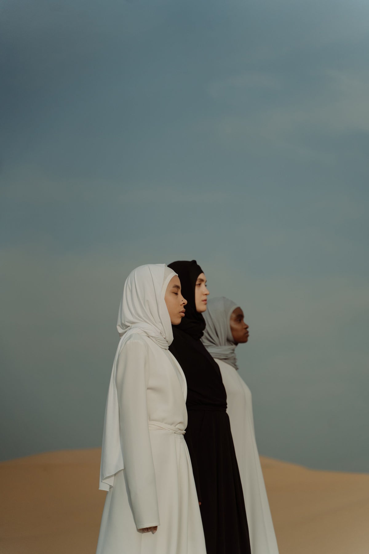 Three women standing together on a desert dune