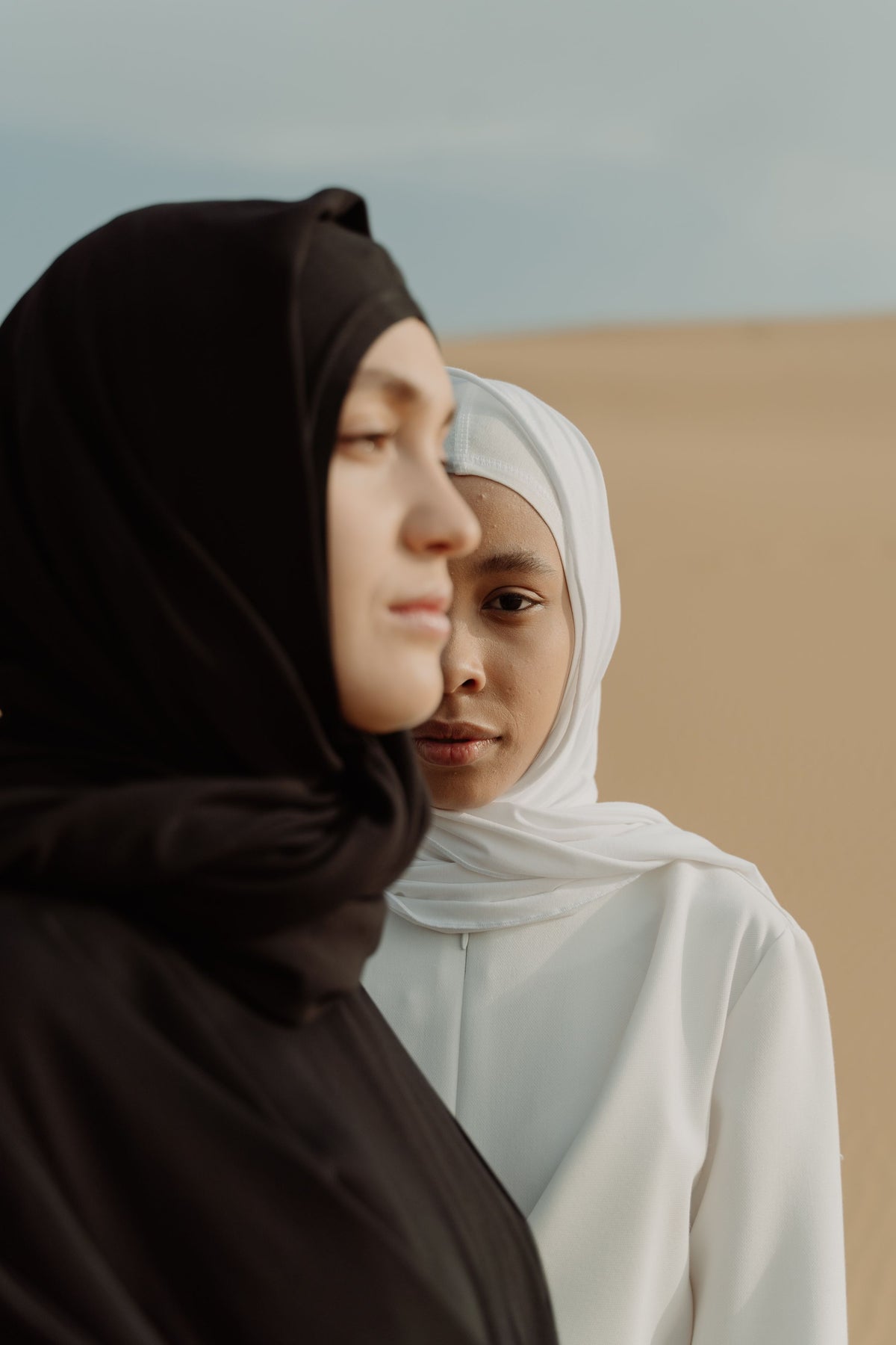 Two women in headscarves standing close together, calm