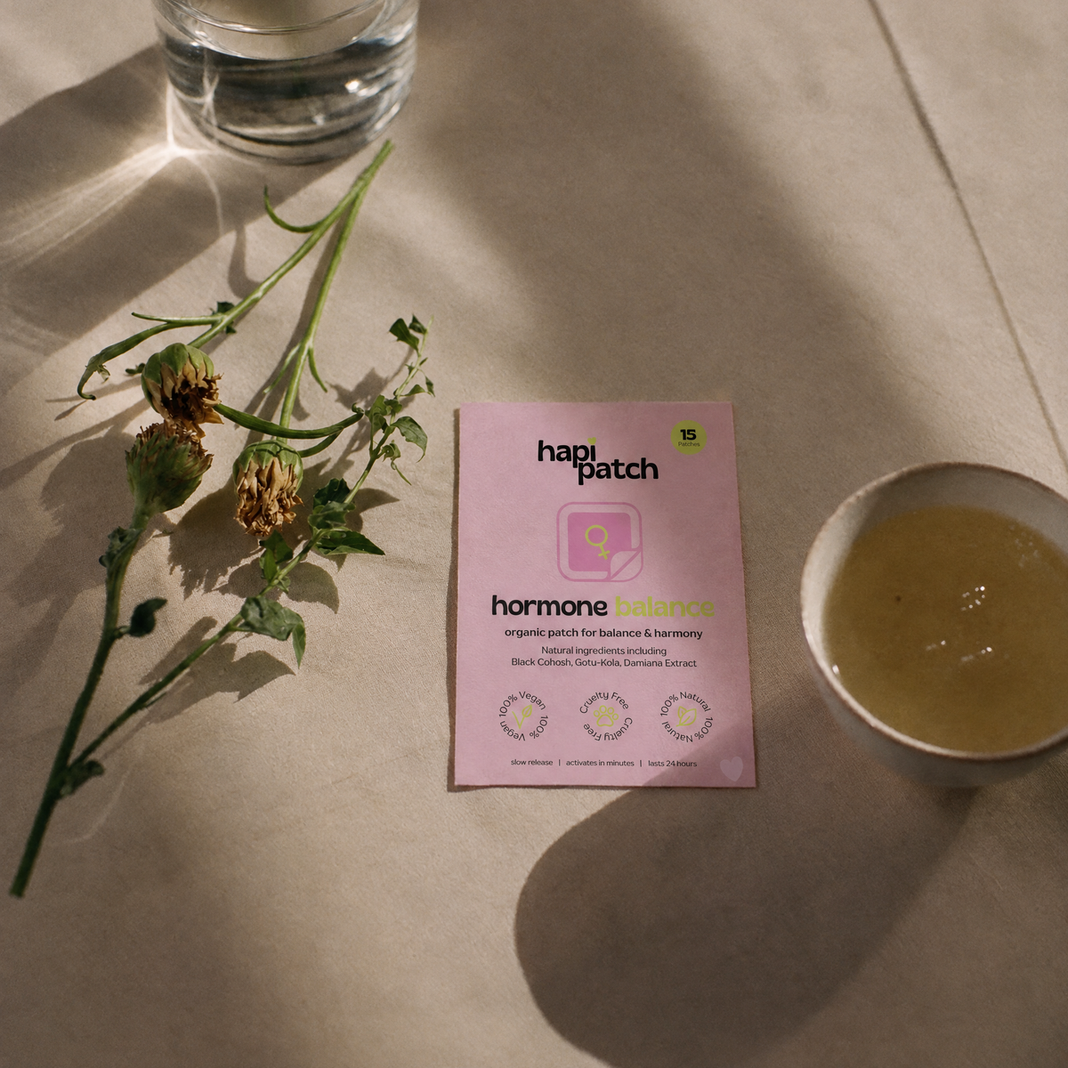 Hapi Patch Cycle & Mood Patches pack on a table with a flower stem and a cup of tea