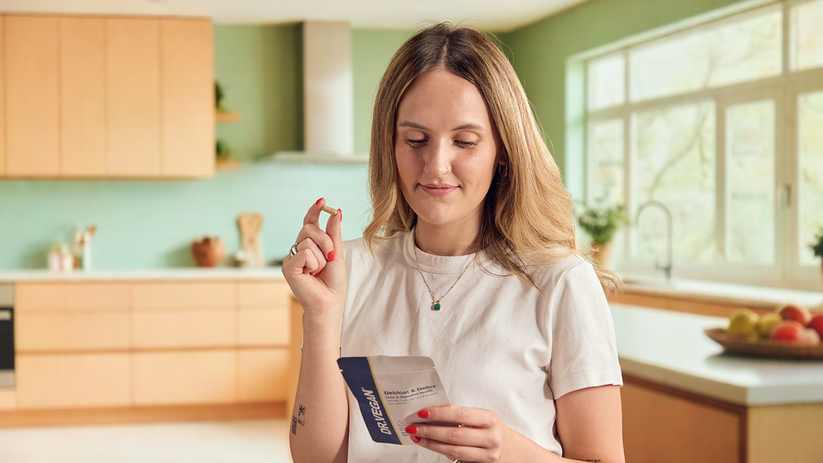 Woman in her kitchen holding a Debloat capsule