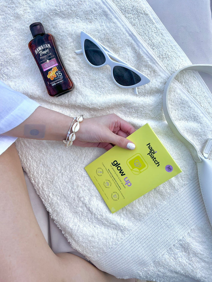 عبوة Hapi Patch Glow Up Patches على منشفة بيضاء مع نظارة شمسية وقارورة