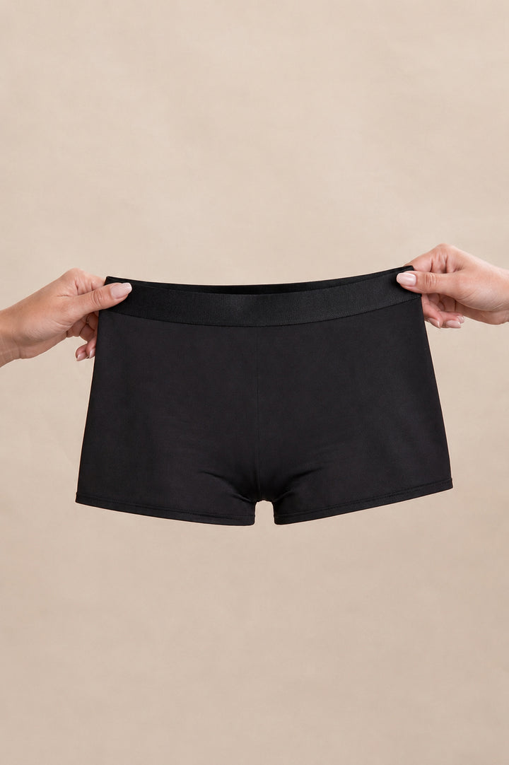 Réjeanne Glow Period Boxer in black held up in both hands to show its size
